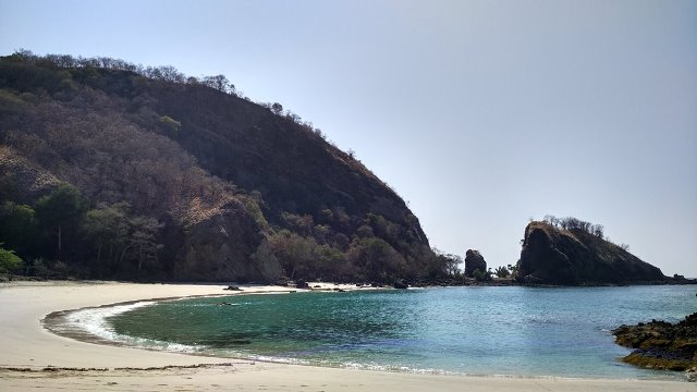 Pantai disisi sebelah kiri yang dihiasi oleh pasir putih lembut serta airnya yang berwarna hijau tosca